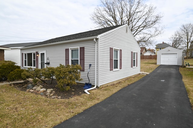 view of side of home with a detached garage, aphalt driveway, and an outdoor structure