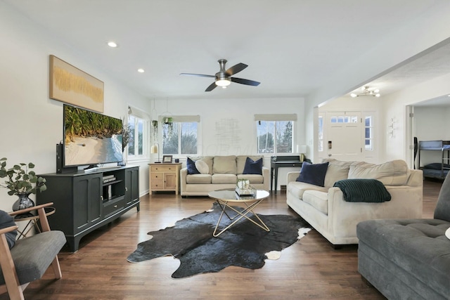 living room featuring dark wood-type flooring and ceiling fan with notable chandelier