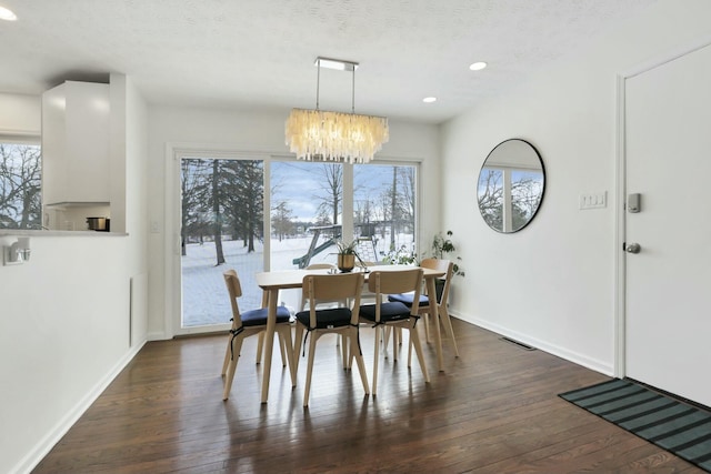 dining room with a textured ceiling, dark hardwood / wood-style flooring, an inviting chandelier, and a healthy amount of sunlight