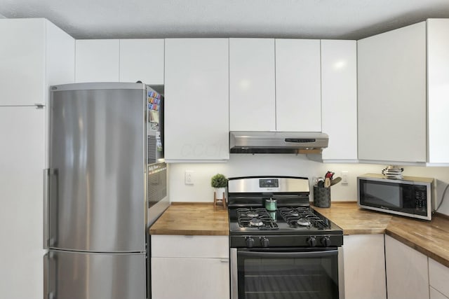 kitchen with white cabinets, stainless steel appliances, and wood counters