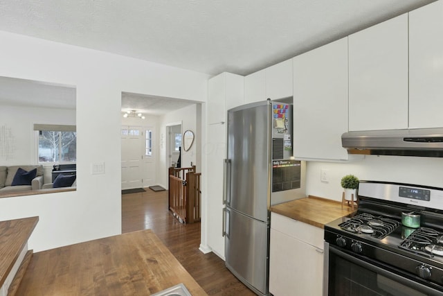 kitchen featuring dark wood-type flooring, black gas range oven, stainless steel fridge, a textured ceiling, and white cabinets