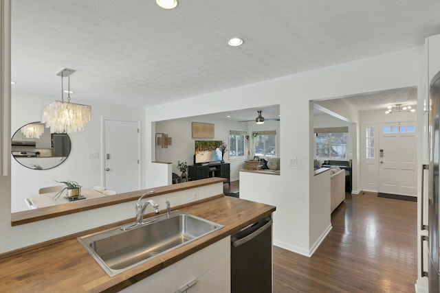 kitchen featuring sink, dark wood-type flooring, stainless steel dishwasher, pendant lighting, and ceiling fan with notable chandelier