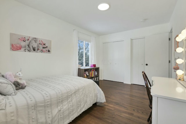 bedroom featuring two closets and dark hardwood / wood-style floors