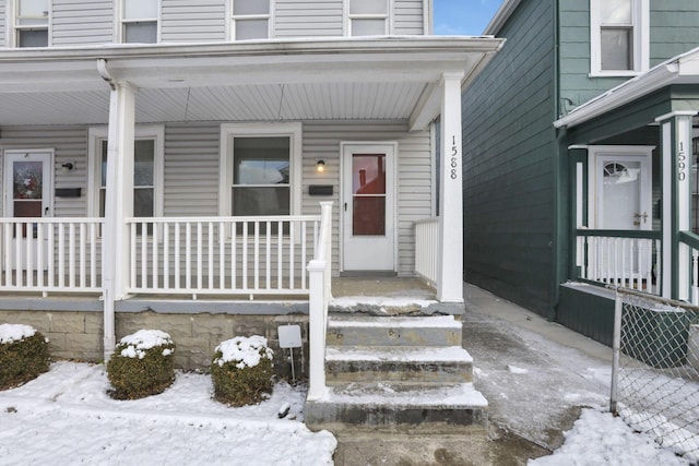 snow covered property entrance with a porch