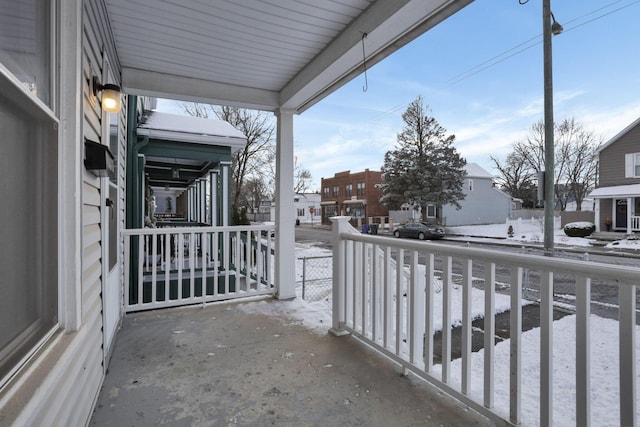 snow covered back of property featuring covered porch