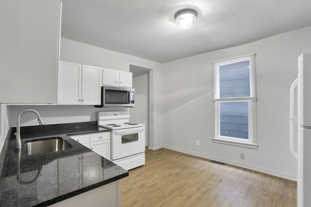 kitchen featuring dark stone counters, white appliances, sink, light hardwood / wood-style floors, and white cabinetry