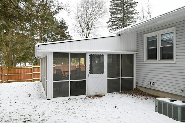 snow covered property with a sunroom and central air condition unit