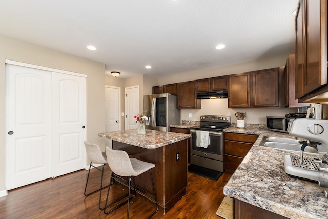 kitchen featuring sink, a kitchen breakfast bar, stainless steel appliances, a center island, and dark hardwood / wood-style flooring