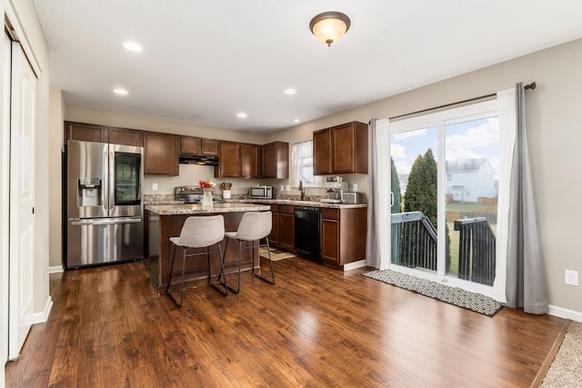 kitchen with sink, a kitchen island, stainless steel appliances, dark hardwood / wood-style floors, and a kitchen bar