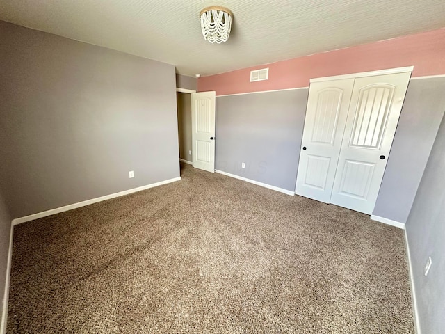 unfurnished bedroom with carpet flooring, a textured ceiling, and a closet