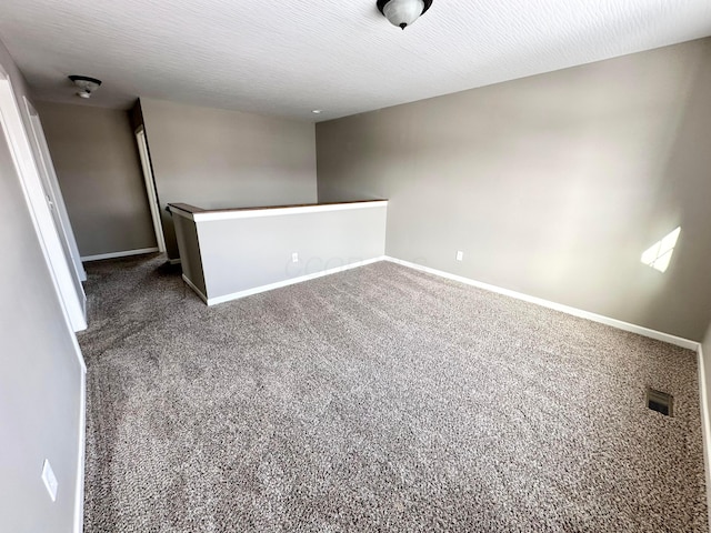 empty room with dark colored carpet and a textured ceiling