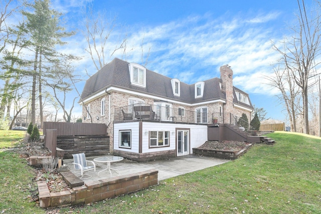 rear view of property with a patio, a balcony, and a lawn