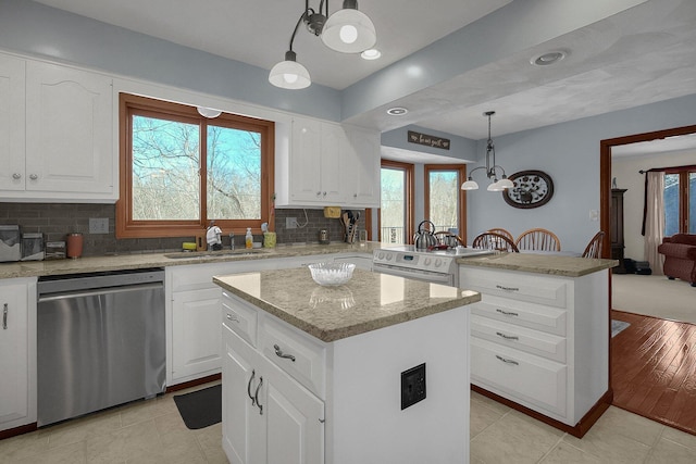 kitchen with pendant lighting, sink, white cabinets, a kitchen island, and stainless steel dishwasher