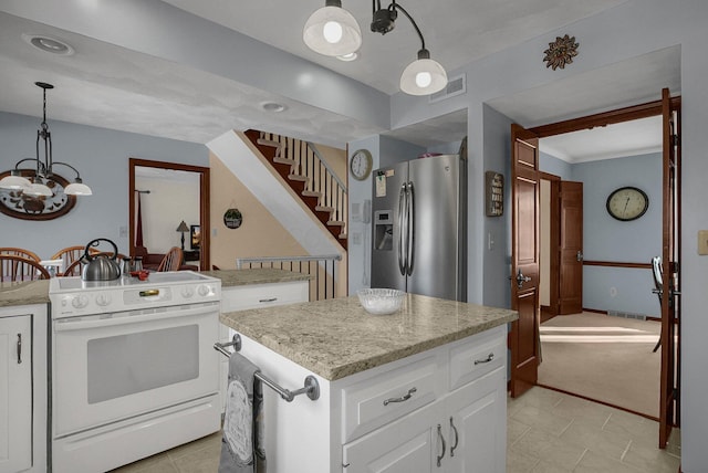 kitchen with hanging light fixtures, stainless steel fridge, a kitchen island, electric stove, and white cabinets