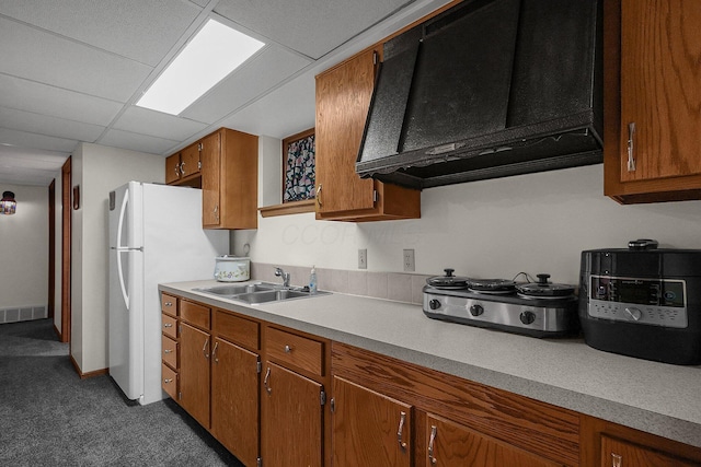 kitchen with sink, a paneled ceiling, white refrigerator, dark carpet, and wall chimney exhaust hood