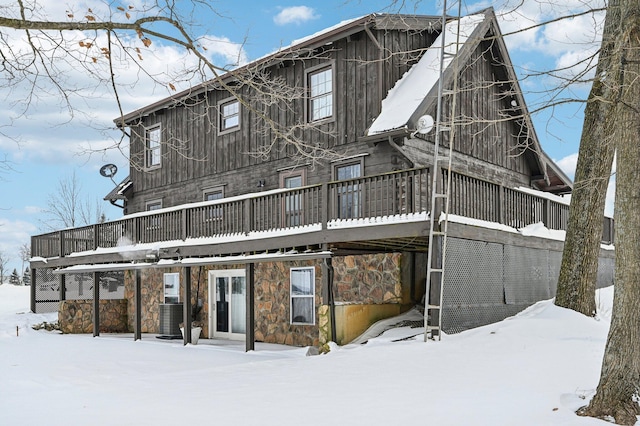 snow covered house featuring central AC unit and a deck