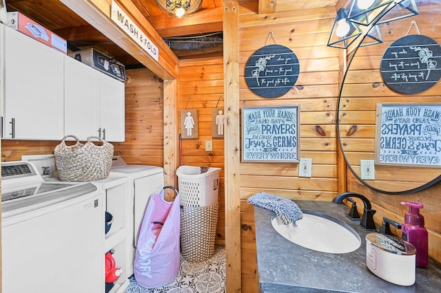 laundry area featuring cabinets, washing machine and dryer, wooden walls, and sink