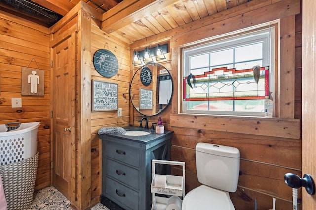 bathroom with beam ceiling, wooden ceiling, wood walls, toilet, and vanity