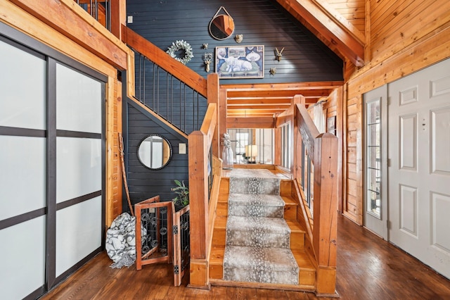 staircase with wooden walls, high vaulted ceiling, and hardwood / wood-style flooring