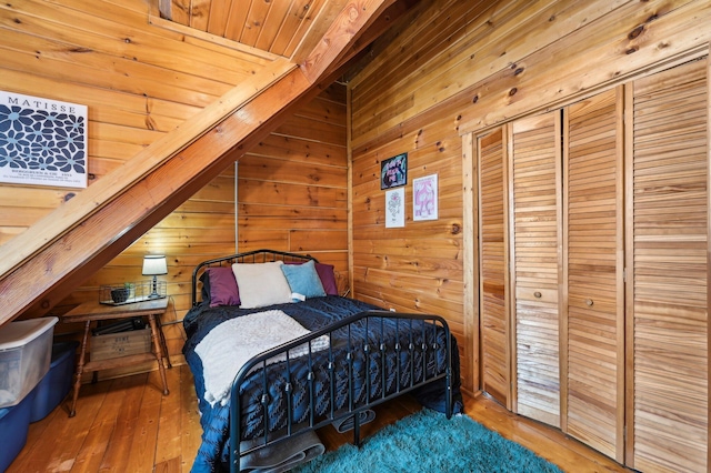 bedroom with wood walls, wooden ceiling, lofted ceiling, and hardwood / wood-style flooring