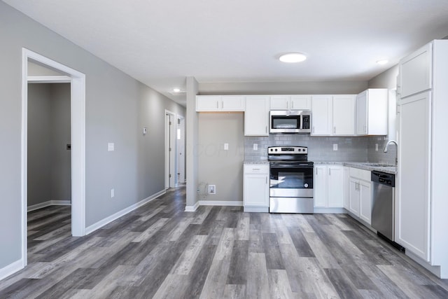 kitchen featuring light stone countertops, appliances with stainless steel finishes, decorative backsplash, sink, and white cabinetry