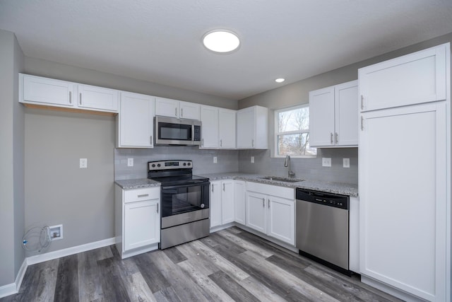 kitchen featuring light stone countertops, stainless steel appliances, white cabinetry, and sink