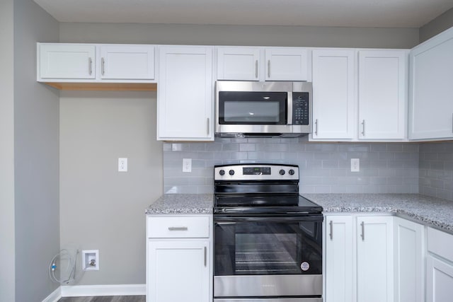 kitchen featuring light stone counters, white cabinets, and stainless steel appliances