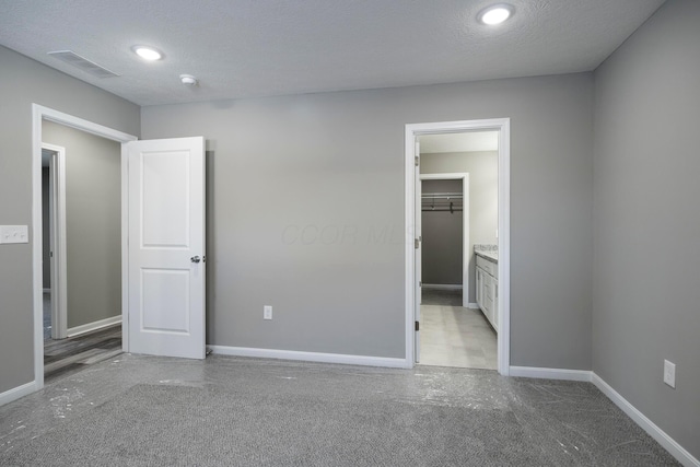 unfurnished bedroom featuring a walk in closet, a textured ceiling, and a closet