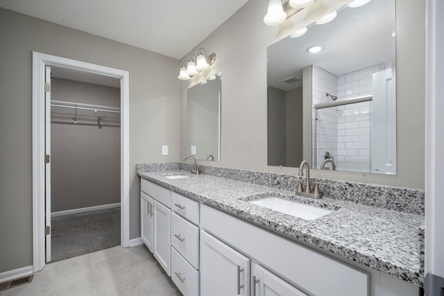 bathroom with tile patterned flooring, vanity, and walk in shower