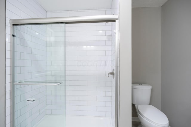 bathroom featuring toilet and a shower with shower door