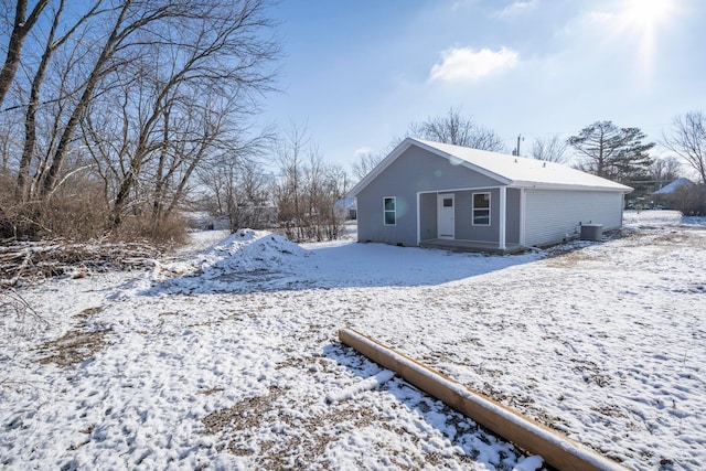 snow covered rear of property featuring cooling unit