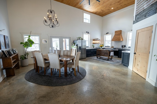 dining room with a high ceiling, concrete floors, a notable chandelier, and wood ceiling