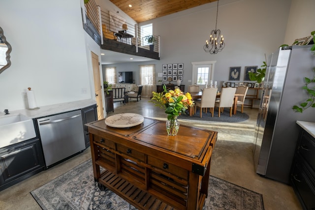 kitchen featuring wooden ceiling, a high ceiling, an inviting chandelier, hanging light fixtures, and appliances with stainless steel finishes