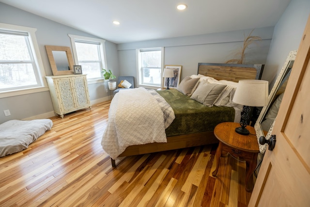 bedroom featuring multiple windows, lofted ceiling, and light wood-type flooring