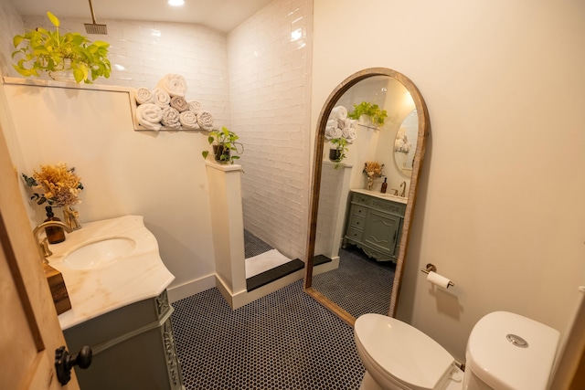 bathroom with vanity, vaulted ceiling, toilet, walk in shower, and brick wall