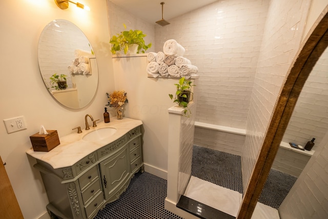 bathroom with tile patterned flooring, vanity, and tiled shower