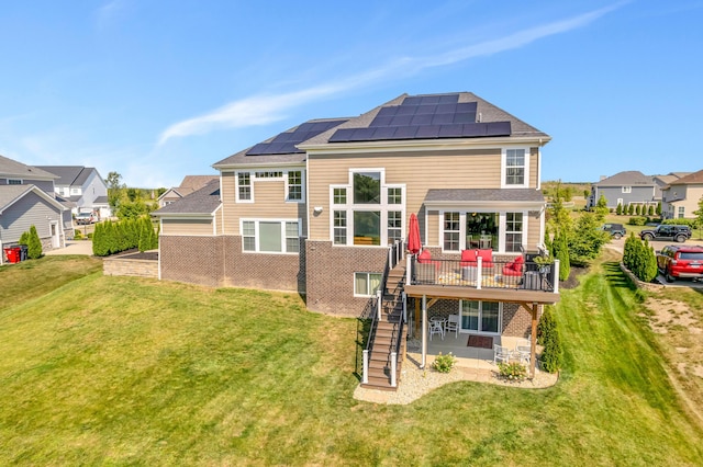 back of property with a lawn, solar panels, a patio area, and a wooden deck