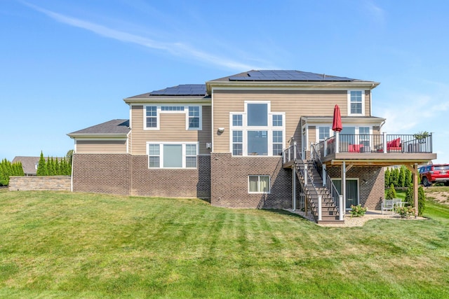 rear view of property featuring a yard, a deck, and solar panels