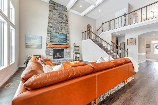 living room with a towering ceiling, a fireplace, coffered ceiling, dark wood-type flooring, and beamed ceiling