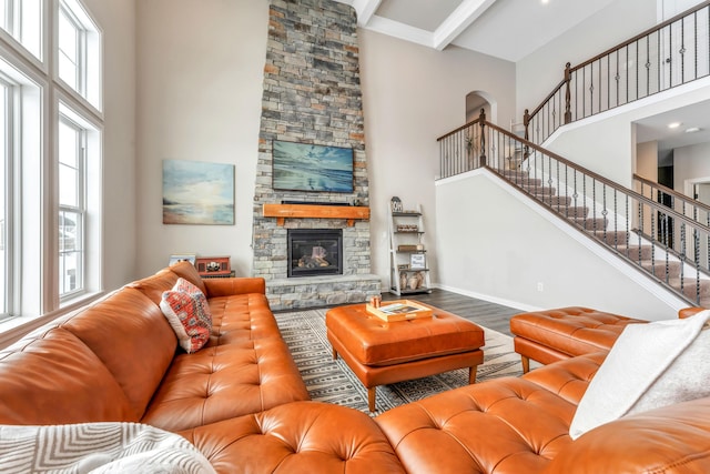 living room with beamed ceiling, wood-type flooring, a fireplace, and a high ceiling