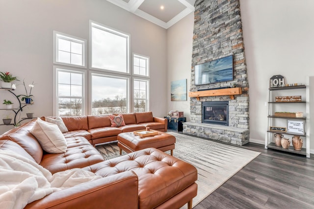 living room with a stone fireplace, dark hardwood / wood-style floors, a towering ceiling, ornamental molding, and beam ceiling