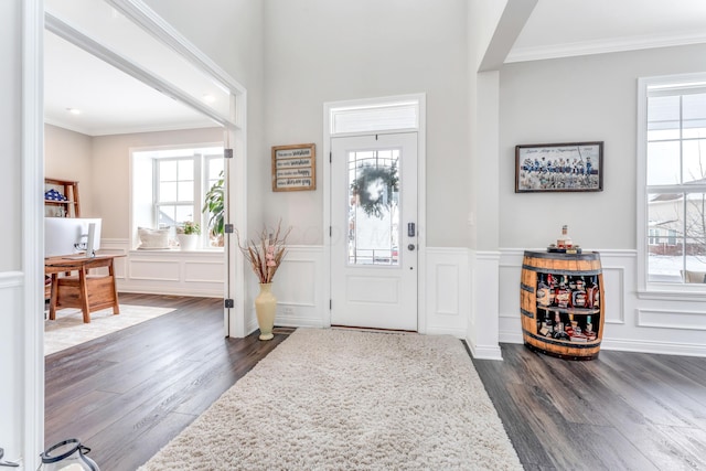 foyer with plenty of natural light, ornamental molding, and dark wood-type flooring