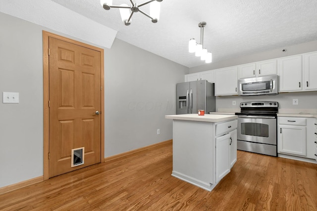 kitchen featuring a center island, hanging light fixtures, stainless steel appliances, a textured ceiling, and white cabinets