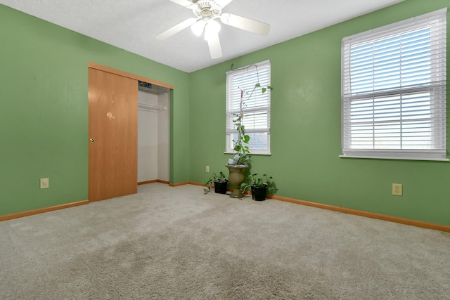 unfurnished bedroom featuring carpet, ceiling fan, and a closet