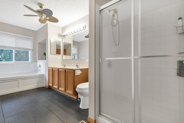 full bathroom featuring ceiling fan, a textured ceiling, toilet, vanity, and independent shower and bath