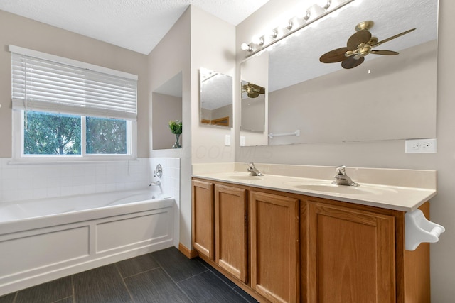 bathroom with a bathing tub, vanity, ceiling fan, and a textured ceiling