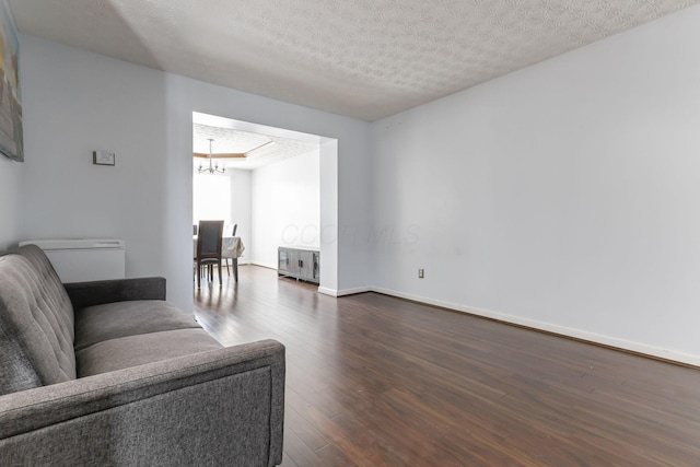 living room with a textured ceiling, dark wood-type flooring, radiator, and a notable chandelier