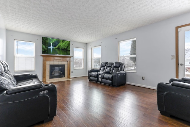 living room with a tile fireplace, dark hardwood / wood-style floors, and a textured ceiling