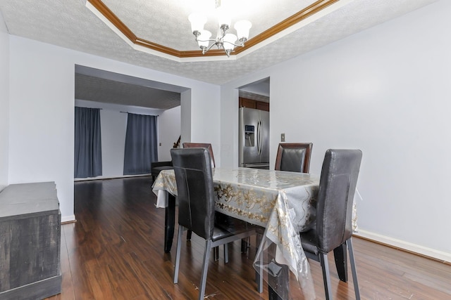 dining space with ornamental molding, a textured ceiling, a raised ceiling, a notable chandelier, and dark hardwood / wood-style floors