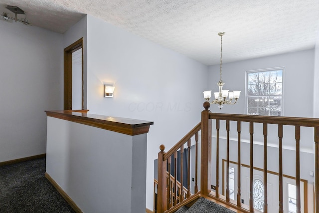 staircase featuring carpet flooring, a textured ceiling, and an inviting chandelier